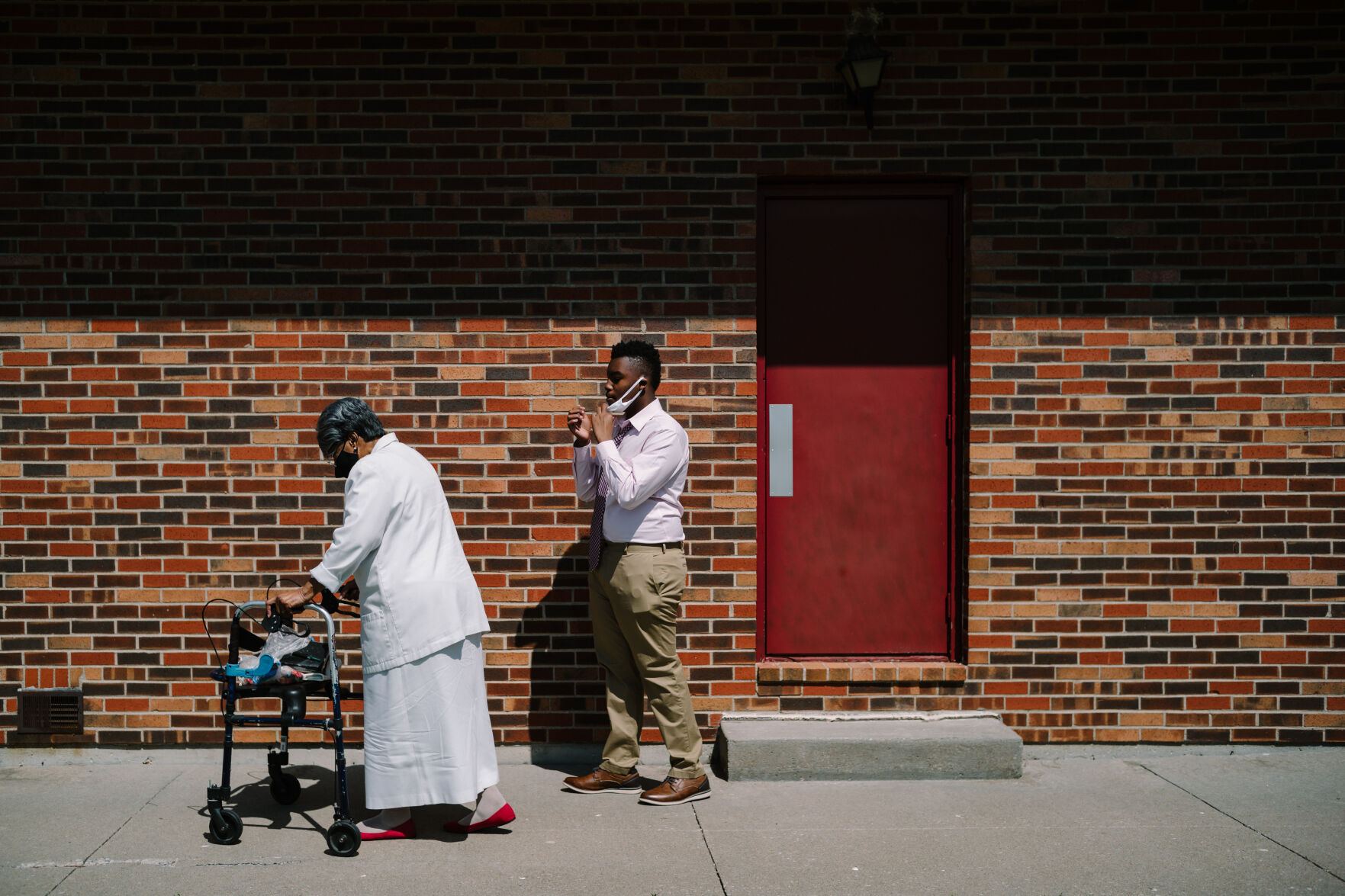 While helping Annie Gardner, left, to her car, Gregg Jackson, 14, pulls his mask over his nose